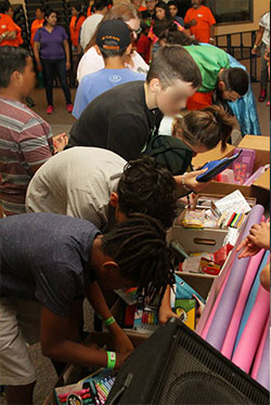 multiple kids looking through boxes filled with school supplies