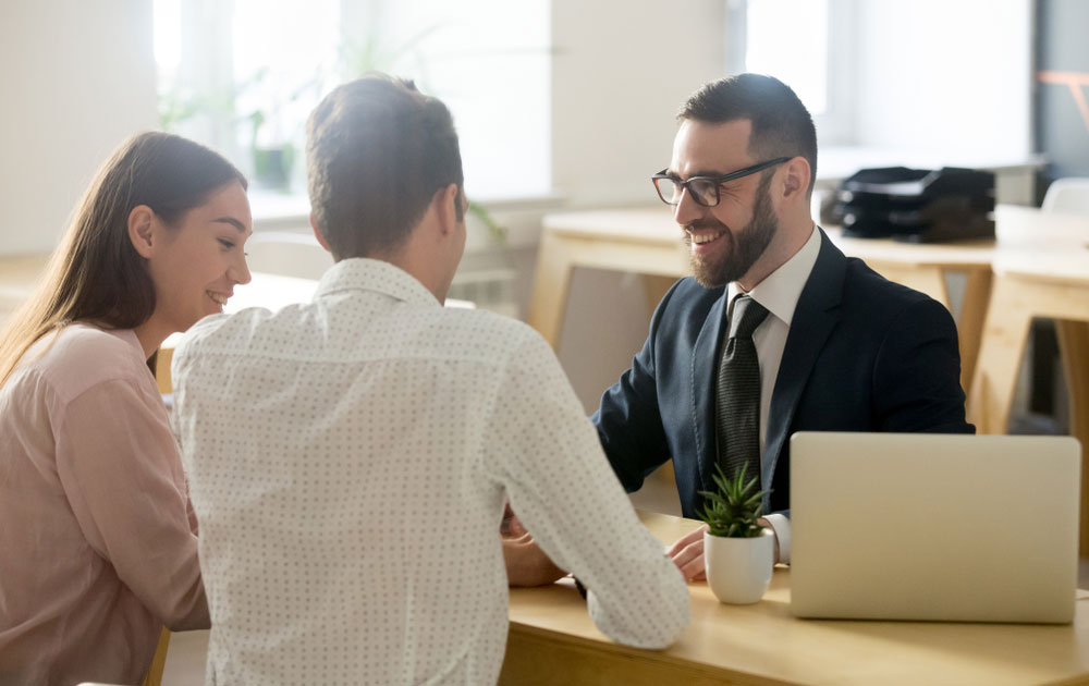 man in glasses speaking with couple