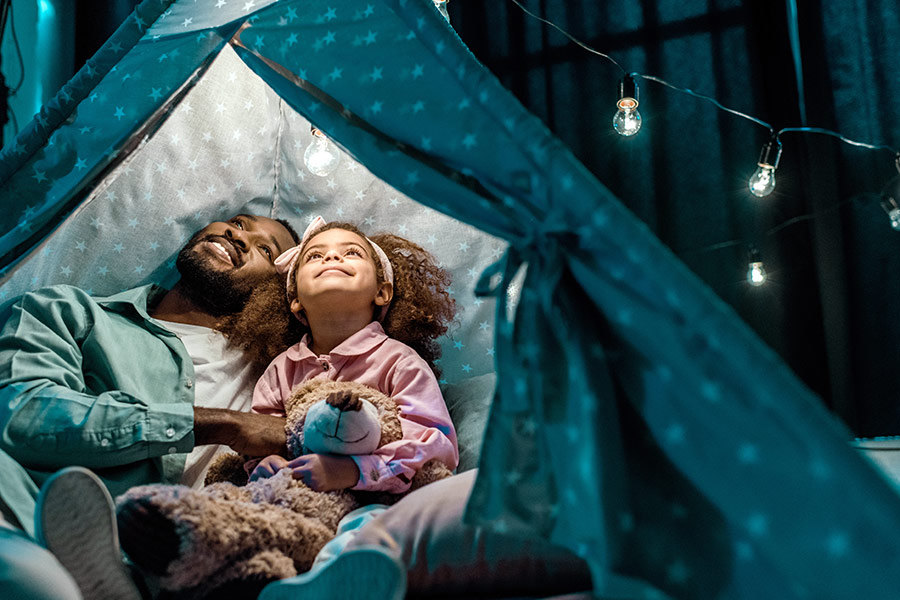 father, daughter and teddy bear admiring their blanket fort in the living room