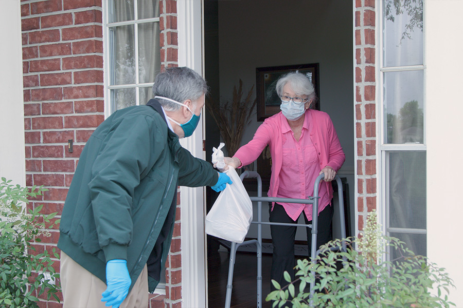 volunteer delivering essentials to an elderly woman during the COVID-19 pandemic