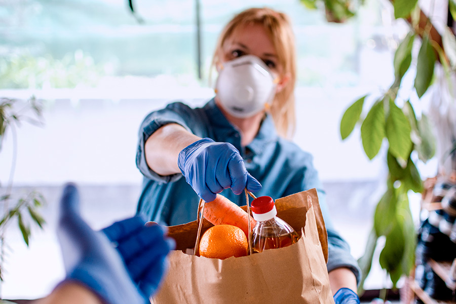 volunteer wearing a protective mask and gloves while delivering groceries