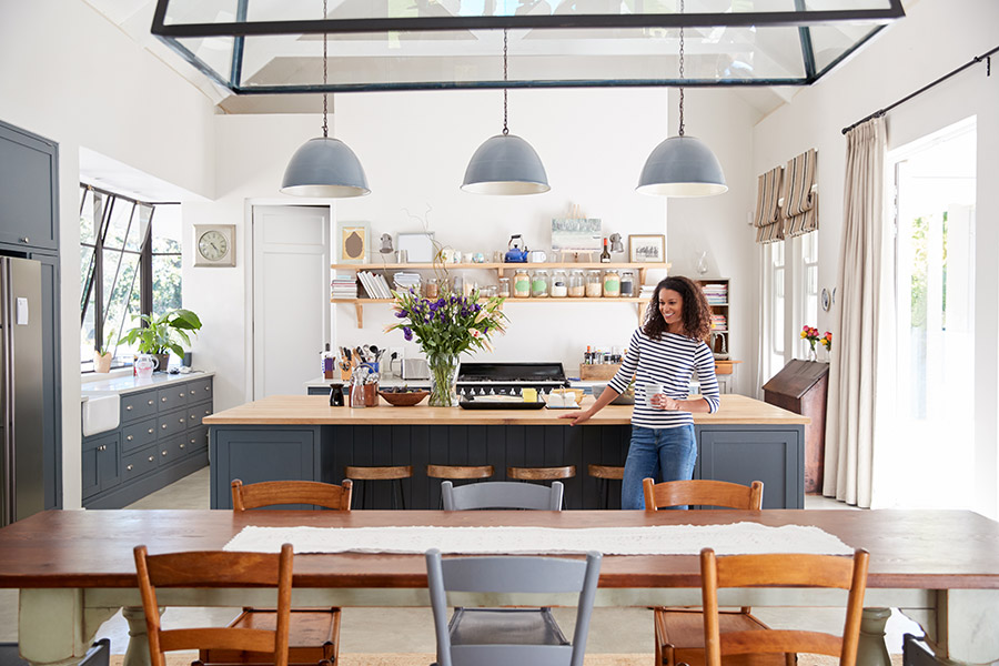 Smiling woman enjoying her open and inviting kitchen and dining area in her new home.