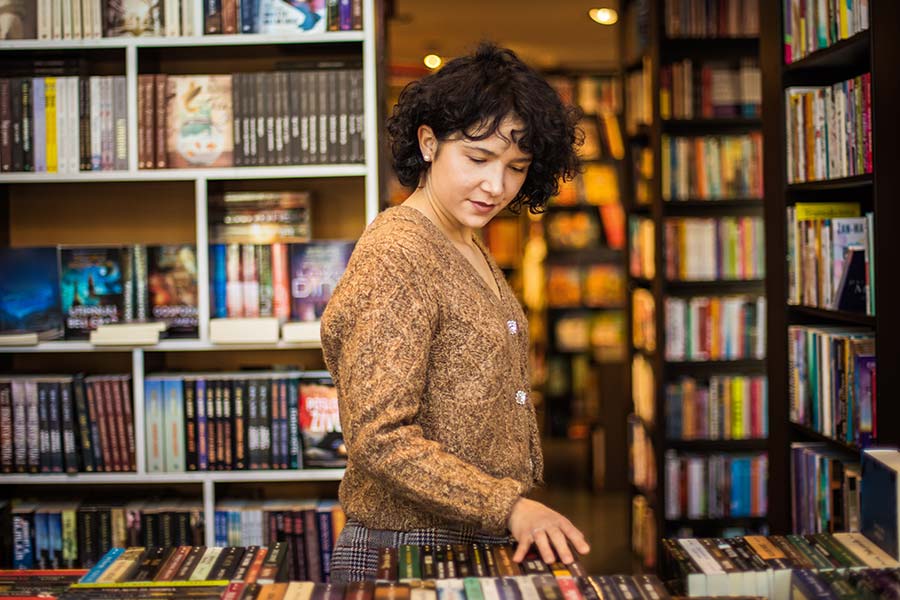 Woman checking out her local library instead of buying new books.