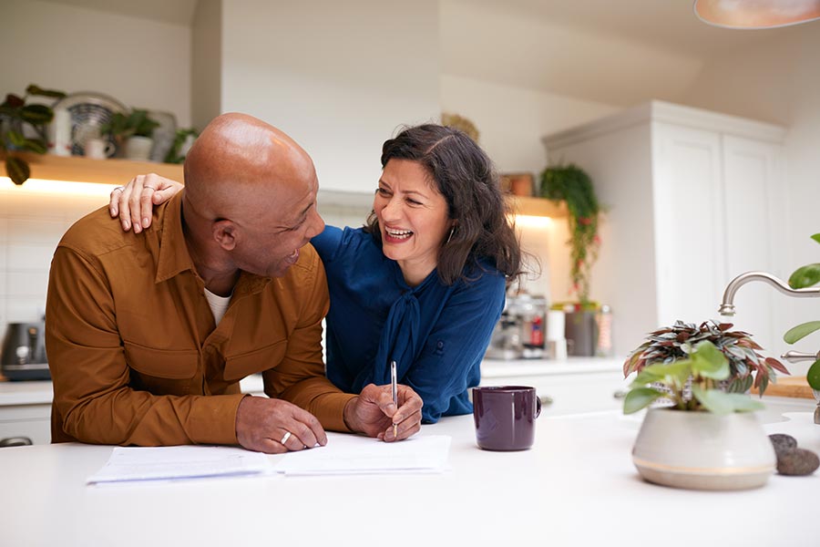 Couple laughing together in the kitchen. Learn how to maximize your savings and which savings account is best for you.