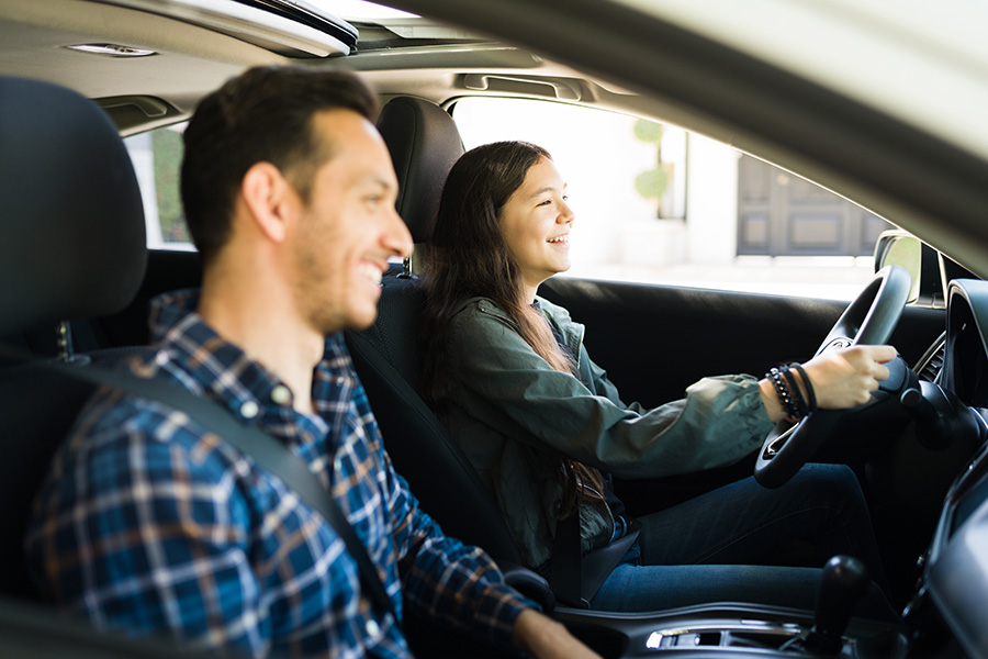 Father and daughter in a car. Learn the benefits and risks of co-signing on an auto loan for your children.